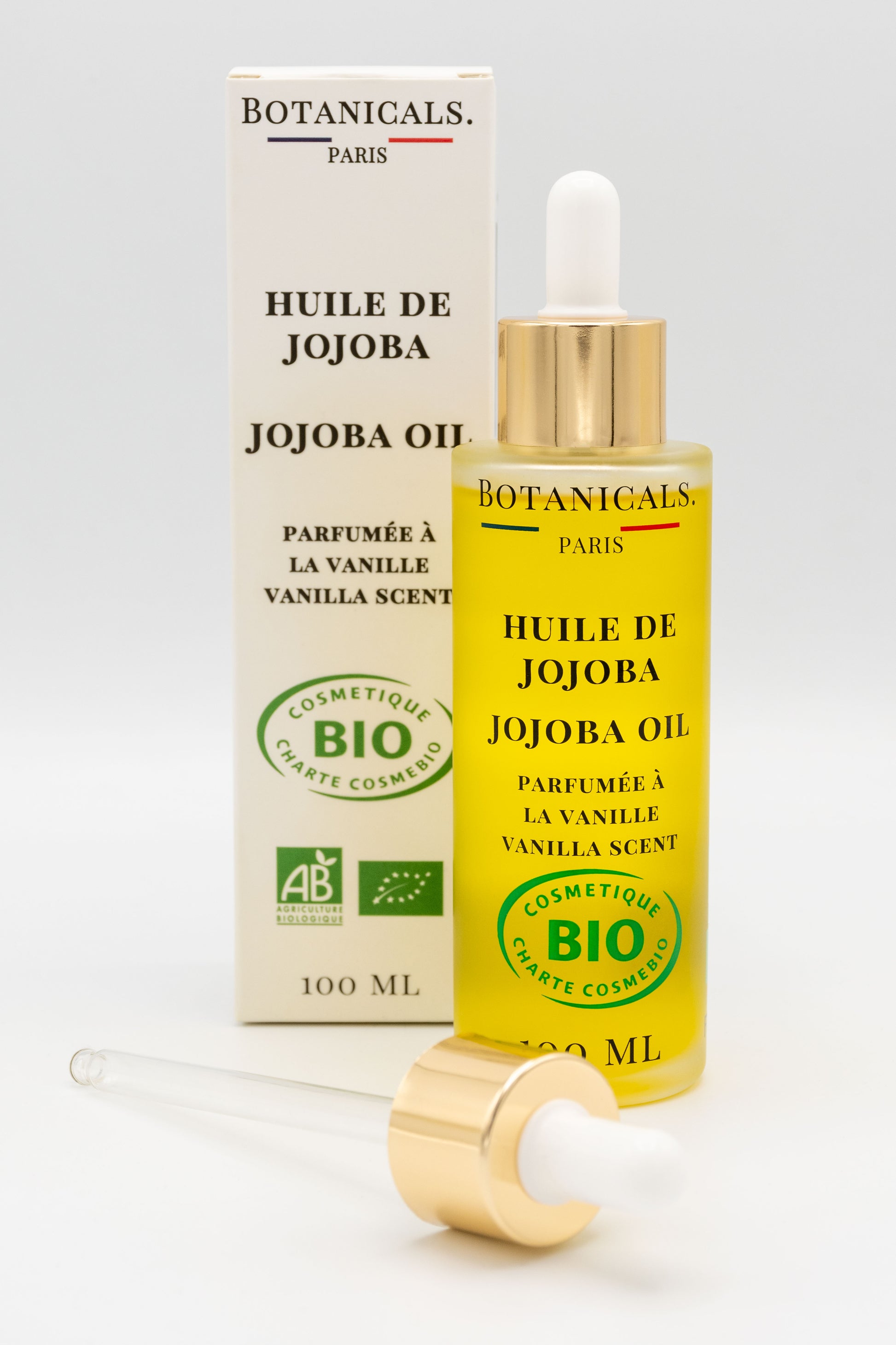 Une bouteille d'huile de jojoba bio 100ml Botanicals devant sa boite, une pipette posé devant