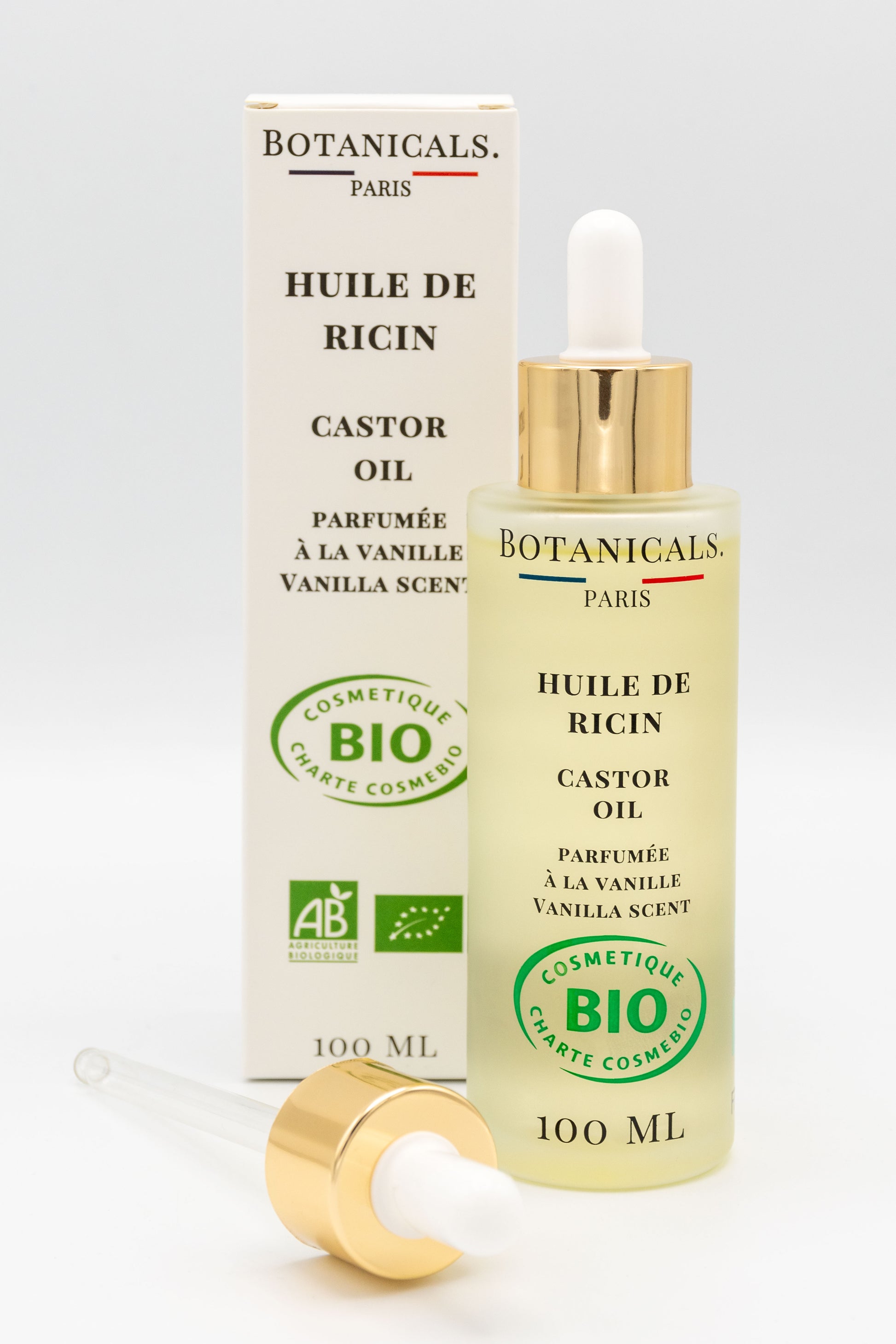 Une bouteille d'huile de ricin bio 100ml Botanicals devant sa boite, une pipette posé devant