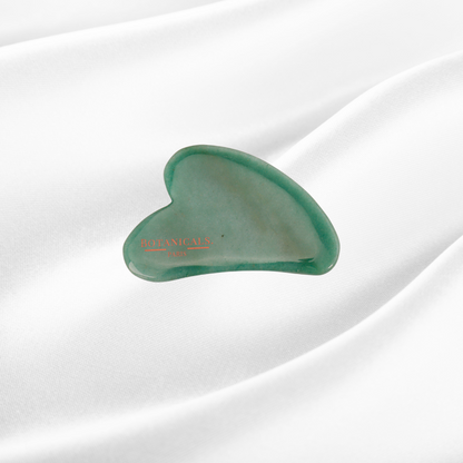 Guasha Botanicals en Jade devant un fond en soie de murier blanc