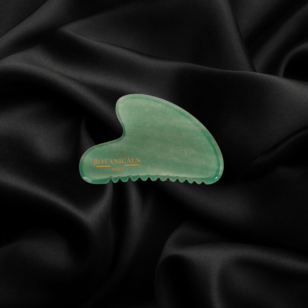 Guasha à dents Botanicals en Jade sur un fond de soie de mûrier noir