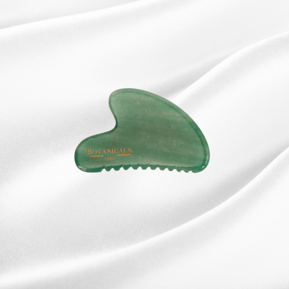 Guasha à dents Botanicals en Jade sur un fond de soie de mûrier blanc