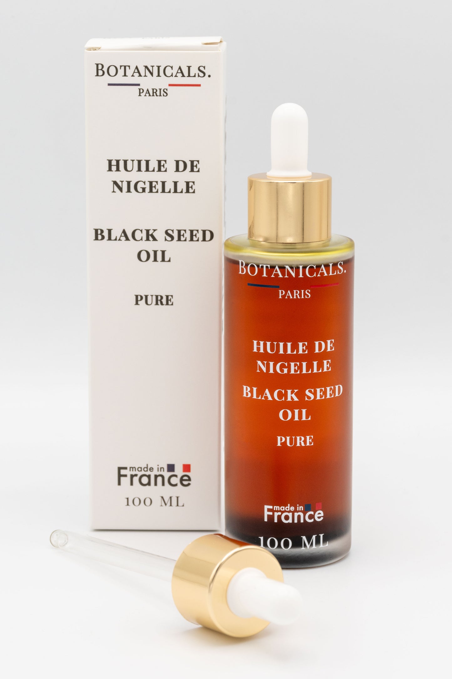 Une bouteille d'huile de nigelle bio 100ml Botanicals devant sa boite, une pipette posé devant