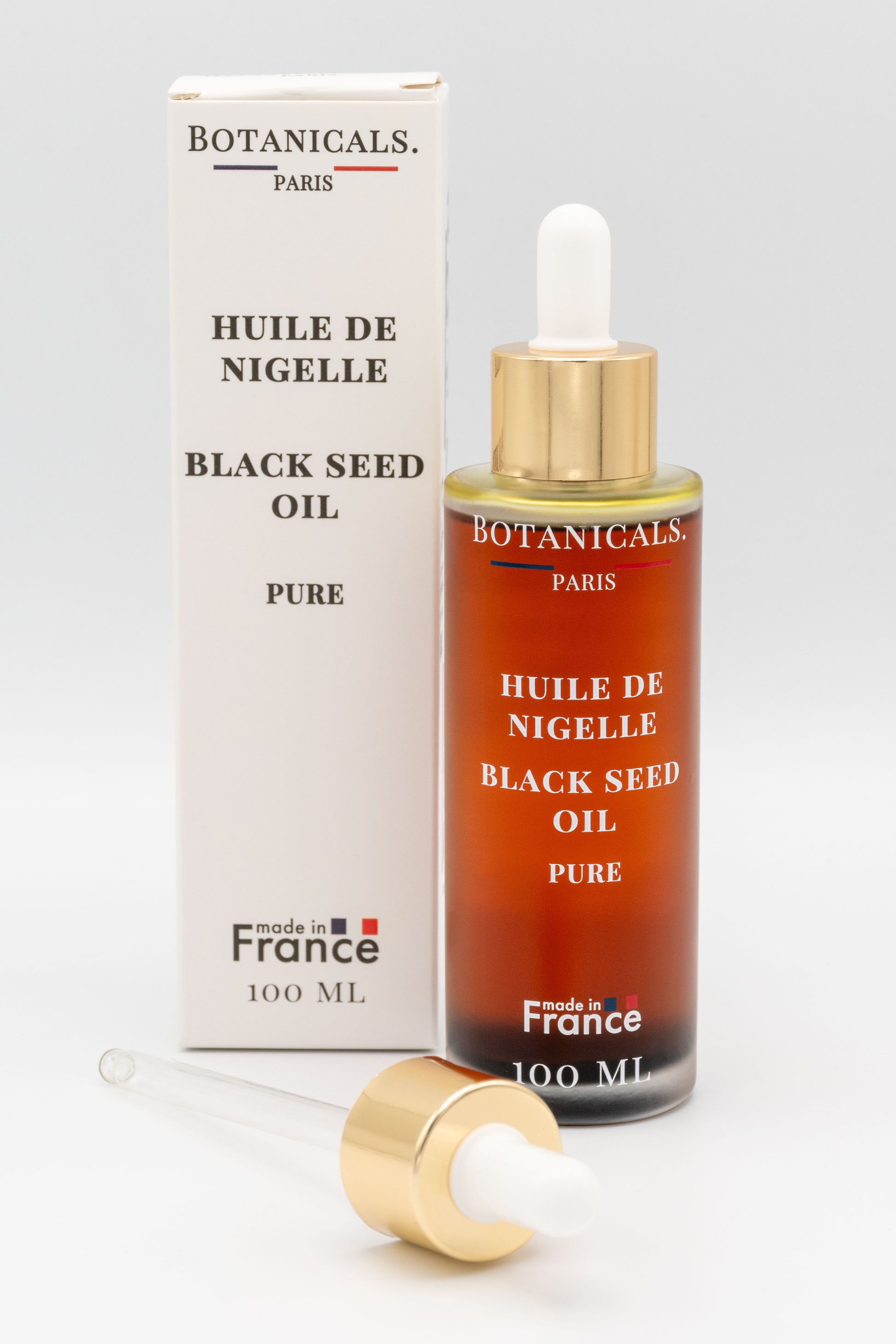 Une bouteille d'huile de nigelle bio 100ml Botanicals devant sa boite, une pipette posé devant