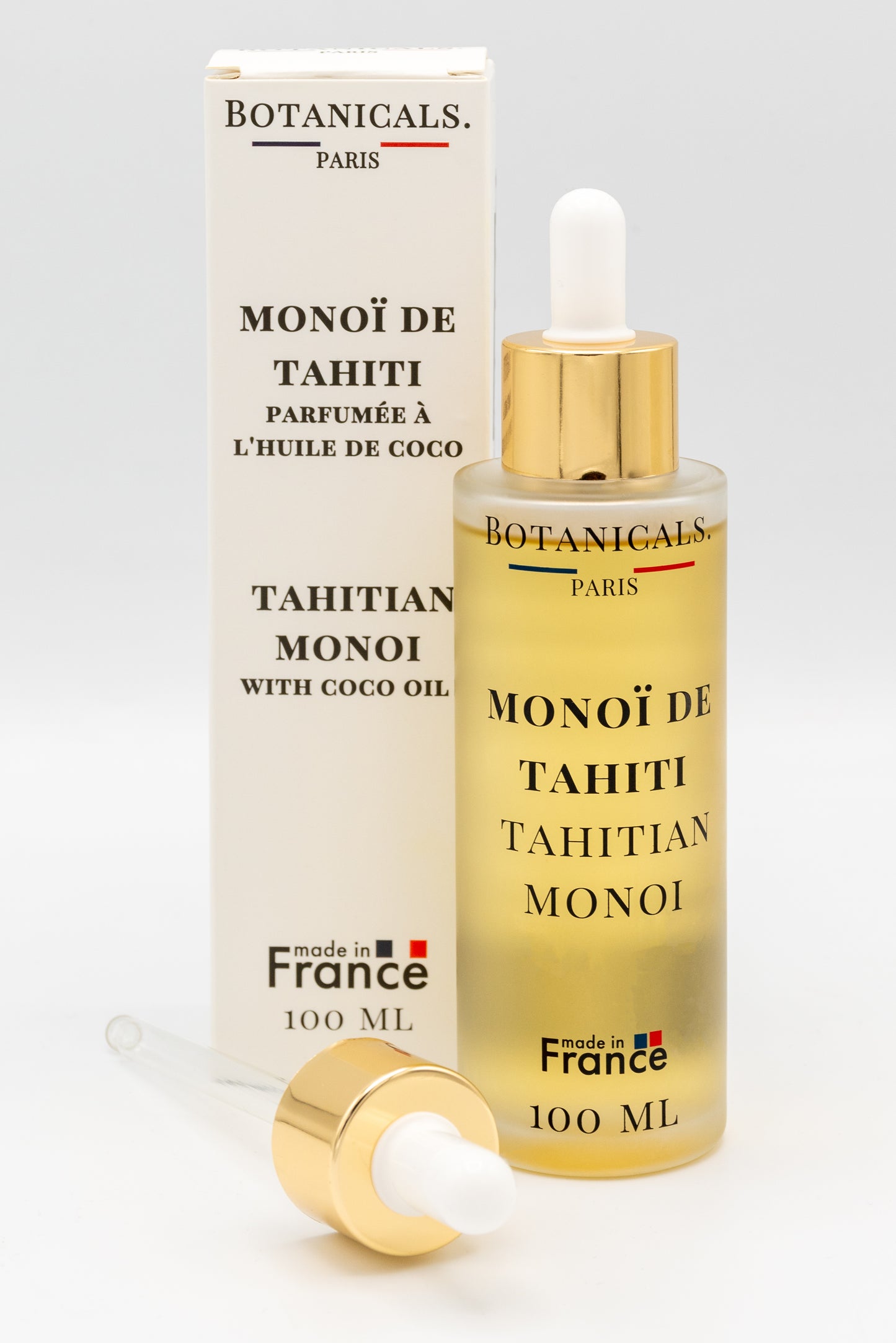 Une bouteille d'huile de monoï de Tahiti enrichi à l'huile de coco bio 100ml Botanicals devant sa boite, une pipette posé devant