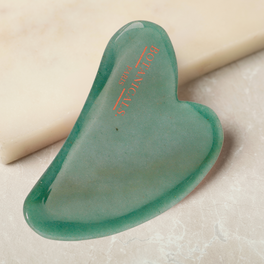 Un guasha  en Jade posé sur un marbre beige