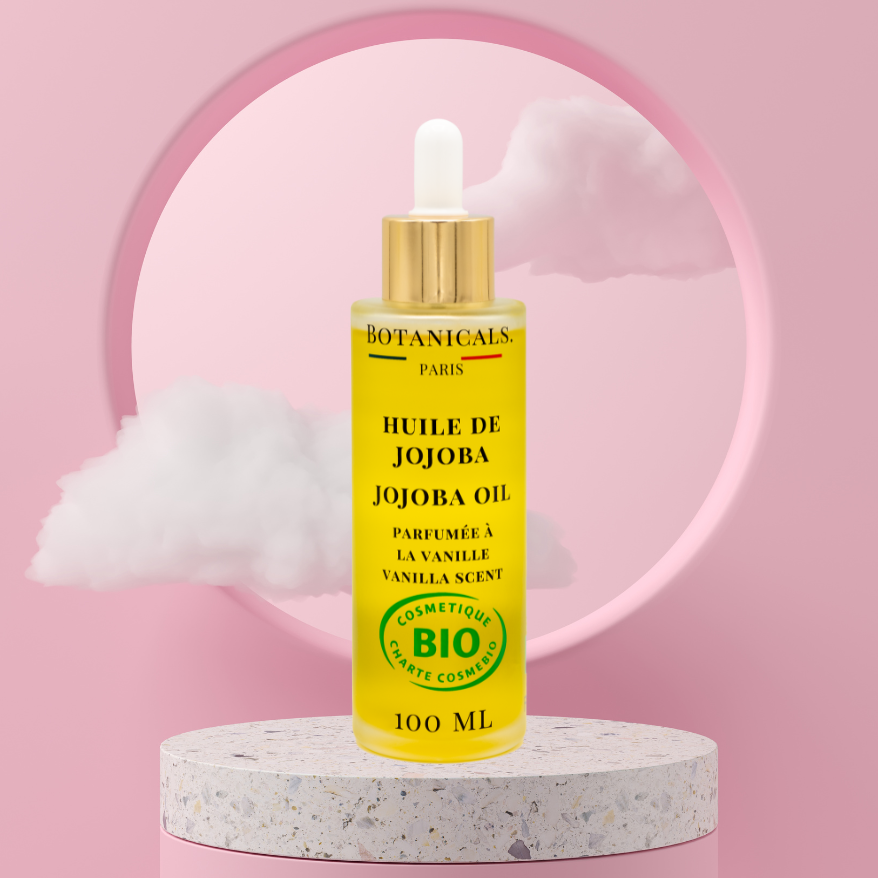 Une bouteille de 100ml d'huile de jojoba bio devant un fond rose, parsemé de léger nuage